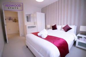 een slaapkamer met een groot wit bed en een rode deken bij Festival Place, Modern Town Center Apartment, Perfect for Contractors & Families, FREE Parking & WiFi by REDWOOD STAYS in Basingstoke