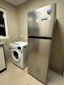 een keuken met een koelkast en een wasmachine bij Palm Inn Hostel in Dubai