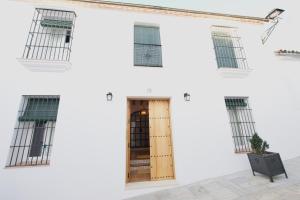 a white building with a wooden door and windows at Casa Rural Sierra Morena in Cazalla de la Sierra