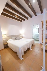 a white bedroom with two beds and a cross on the wall at Casa Rural Sierra Morena in Cazalla de la Sierra