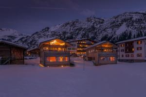 a large building in the snow in front of a mountain at Design Chalets Lech in Lech am Arlberg