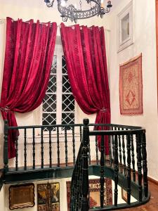 una ventana con cortinas rojas junto a una escalera en The Yellow Mansion! Αγιος Γεώργιος Νηλείας Πήλιο, en Agios Georgios Nilias