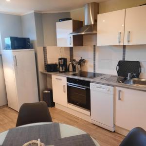 a kitchen with white cabinets and a stove top oven at Theunis Ferienwohnung in Ostseebad Karlshagen