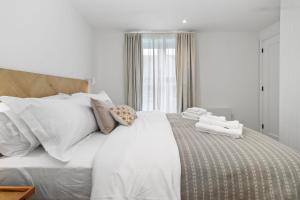 uma cama branca com lençóis brancos e almofadas em Home Away from Home Stylish Apartment Retreat em Eastbourne