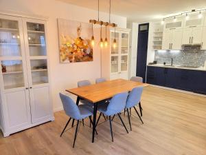 艾德的住宿－Moonshine Érd，一间带木桌和蓝色椅子的用餐室