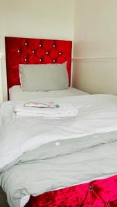 a white bed with a red headboard and a red blanket at Quiet Single bedroom with free parking, office desk &chair, free wifi in Harrowden