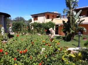 a garden in front of a house with flowers at Relais Fenicottero Rosa in Porto San Paolo