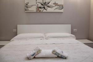 Una cama blanca con dos toallas blancas. en Casa Franca en Maracalagonis