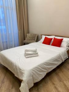 Apartaments COSTA ЖК Алпамыс في أستانا: سرير أبيض كبير مع وسائد حمراء وكرسي