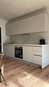 cocina con armarios blancos y microondas en Atrium Apartments Aachen, en Aachen