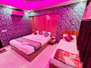 2 Betten in einem Zimmer mit rosafarbener Beleuchtung in der Unterkunft hotel the paradise inn in Neu-Delhi