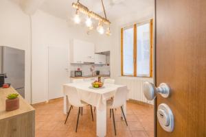 une cuisine et une salle à manger avec une table et des chaises blanches dans l'établissement City Center Piazza Pomposa Suite, à Modène