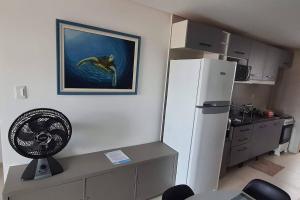 a kitchen with a refrigerator and a desk with a fan at Condomínio Porto de Soleil in Porto De Galinhas