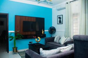 Sala de estar azul con sofá y TV en 3Tee Serviced Apartment Abeokuta en Abeokuta