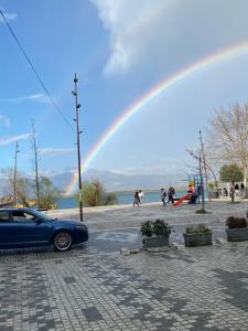 a blue car parked in a parking lot with a rainbow at Welcome Guest House in Shkodër