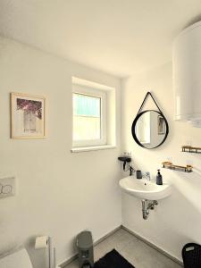 a white bathroom with a sink and a mirror at Bird Home Room 11 in Klagenfurt