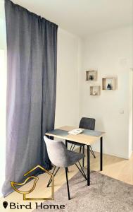 a table and a chair in a room with a curtain at Bird Home Room 11 in Klagenfurt