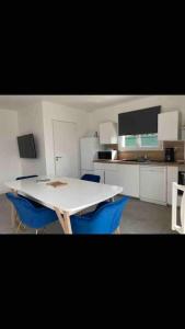 eine Küche mit einem weißen Tisch und blauen Stühlen in der Unterkunft Maison tout confort in Cambo-les-Bains