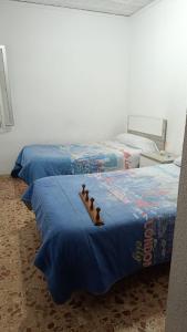 2 camas con sábanas azules en una habitación en Hospedaje El Paseo, en Cocentaina