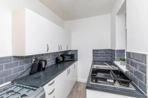 a kitchen with white cabinets and black counter tops at Colston 5 Bedroom House Newcastle in Newcastle upon Tyne