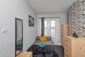 - une chambre avec un lit avec un miroir et un mur en briques dans l'établissement Colston 5 Bedroom House Newcastle, à Newcastle upon Tyne