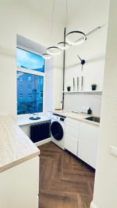 eine Küche mit weißen Schränken, einem Waschbecken und einem Fenster in der Unterkunft Elegant Central park Apartment in Daugavpils