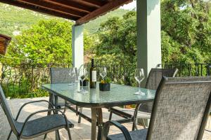a table with wine glasses and a bottle of wine at Armonia Holiday Home Corfu with King size Bed and Private Garden in Áyios Pandeleḯmon