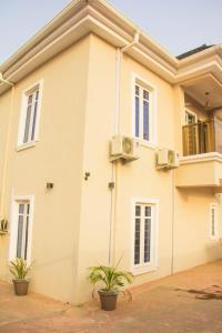 a white house with two plants in front of it at 3Tee Serviced Apartment Abeokuta in Abeokuta