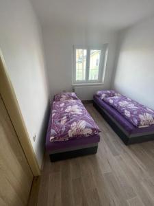 two beds in a room with purple sheets at Ferie Apartman 2 in Děčín
