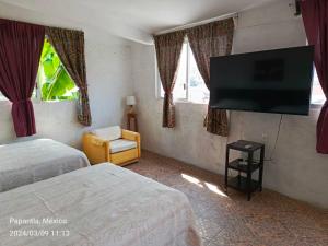 a hotel room with two beds and a flat screen tv at Posada Familiar Papantla in Papantla de Olarte