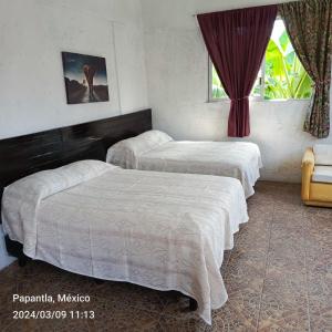 a bedroom with two beds and a window at Posada Familiar Papantla in Papantla de Olarte