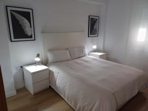 1 dormitorio con 1 cama blanca y 2 mesitas de noche en MATISSE, en Sevilla