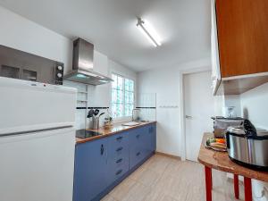 une cuisine avec des armoires bleues et un réfrigérateur blanc dans l'établissement Fee4Me Casa Emilia few meters from the beach, à Lajita