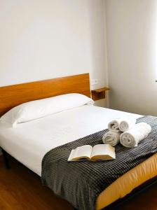 a bedroom with a bed with a book and towels at HOLIDAY HOMES Figueras AT in Castropol
