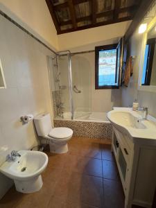 een badkamer met 2 wastafels, een toilet en een douche bij Posada Alegria in Medina Sidonia