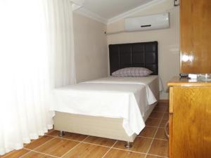 a bedroom with a bed with a black headboard at Avsa Cane Motel in Avşa Adası