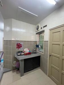 a kitchen with a counter and a sink and a door at HOMESTAY PANDAN 10 in Melaka