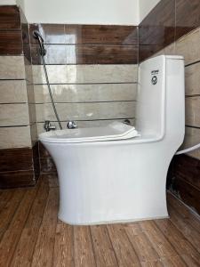 een wit toilet in een badkamer met houten wanden bij Shri Ram International Home Stay Ayodhya in Ayodhya