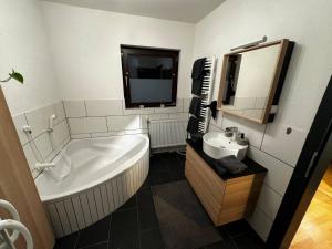 a bathroom with a tub and a sink and a mirror at Wohnung mitten im Salzkammergut in Ohlsdorf