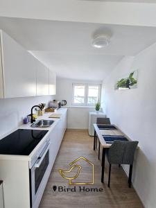 a kitchen with white counters and a sink and a table at Bird Home Room 15 in Klagenfurt