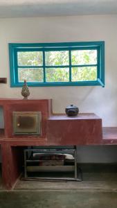 una finestra in una stanza con una panchina rossa con una ciotola sopra di Casa do Bosque a Aiuruoca