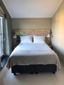 ein Schlafzimmer mit einem großen Bett mit weißen Kissen in der Unterkunft Bij van der Veer in Julianadorp