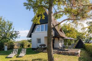 Wendelstorf的住宿－Reetgedecktes Traumhaus mit Panorama-Ostseeblick，草坪上带茅草屋顶和椅子的房子