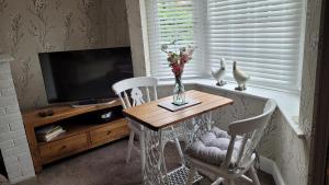 einem Esstisch mit 2 Stühlen und einem TV in der Unterkunft Mulberry Annexe in Felixstowe