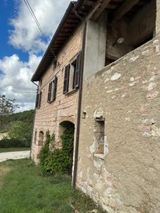 un antiguo edificio de ladrillo con ventanas en el lateral. en Casale nella campagna umbra, en Costacciaro