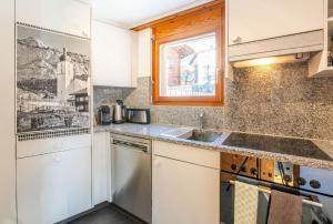 eine Küche mit weißen Schränken, einem Waschbecken und einem Fenster in der Unterkunft Casa Seraina - im Herzen von Flims in Flims