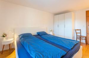 Schlafzimmer mit einem blauen Bett, einem Tisch und einem Stuhl in der Unterkunft Casa Seraina - im Herzen von Flims in Flims