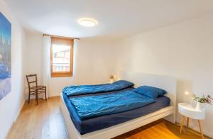 Schlafzimmer mit einem Bett mit blauer Bettwäsche und einem Stuhl in der Unterkunft Casa Seraina - im Herzen von Flims in Flims