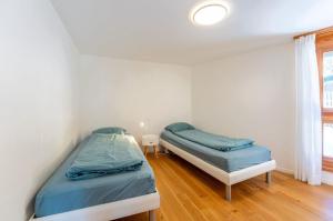 2 Einzelbetten in einem Zimmer mit Fenster in der Unterkunft Casa Seraina - im Herzen von Flims in Flims