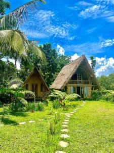 a house with a thatch roof and a pathway at Girang Rinjani Bungalows in Tetebatu